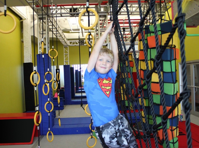a young boy swings across a kids ninja warrior fitness challenge at the fitness equation gym