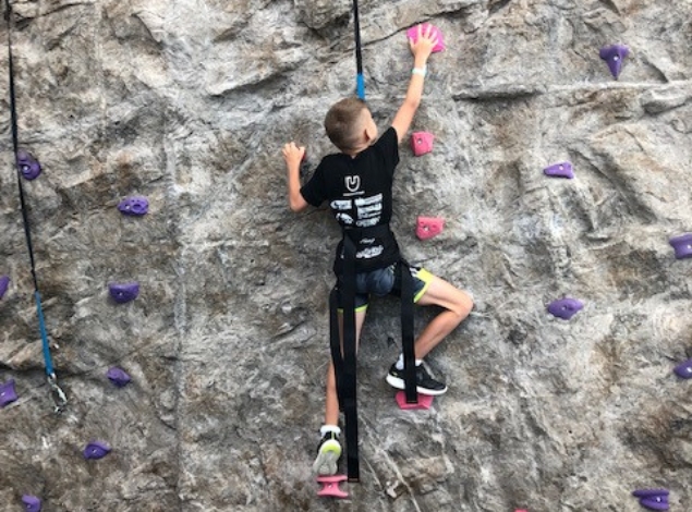 a kid climbs a rock wall at the kidz club at the fitness equation gym in virginia